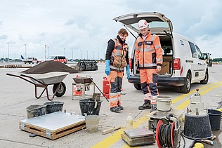 Zwei Kolleg:innen stehen zusammen auf der Baustelle