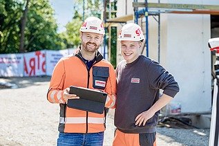 Foto Zwei Bauarbeiter mit weißen Helmen blicken in die Kamera