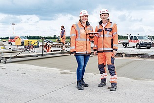 Zwei Kolleg:innen stehen zusammen auf der Baustelle