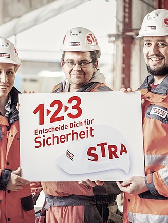 Foto Drei Personen mit Schild in der Hand