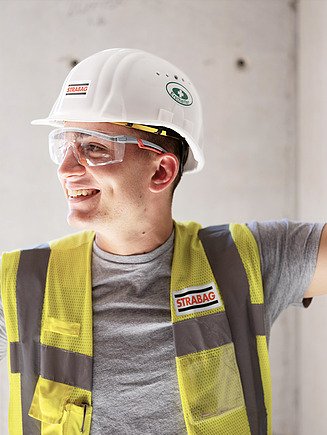 Photo Employee with high-visibility vest, construction helmet and safety goggles looks to the side