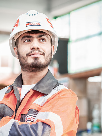 Foto Mann mit Helm und verschränkten Händen schaut nach oben rechts