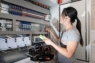 A woman stands in front of an electricity box