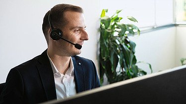 Foto Mann mit Head-Set am Bildschirm sitzend