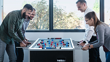 Foto Vier Personen am Fussball-Tischkicker