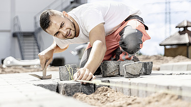 Foto: Marcel Voth beim Verlegen von Pflastersteinen