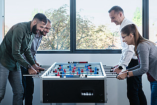 Foto Vier Personen am Fussball-Tischkicker