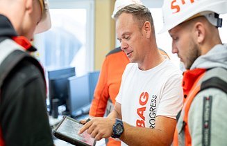 A foreman explains something to his team on a tablet