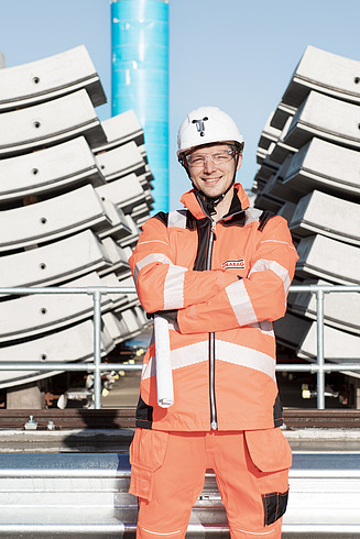 A man between two buildings smiling in the camera