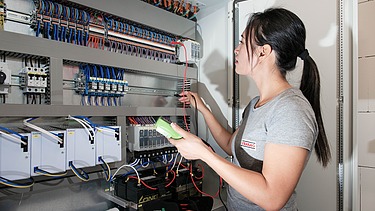 A woman stands in front of an electricity box